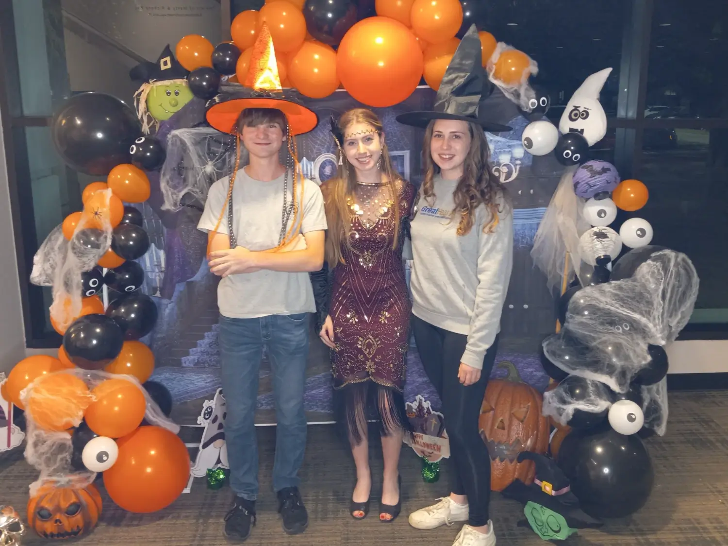 10-30-2024 - Halloween rehearsal photo 89 - Benny, Reagan, and Emily in front of the Halloween backdrop